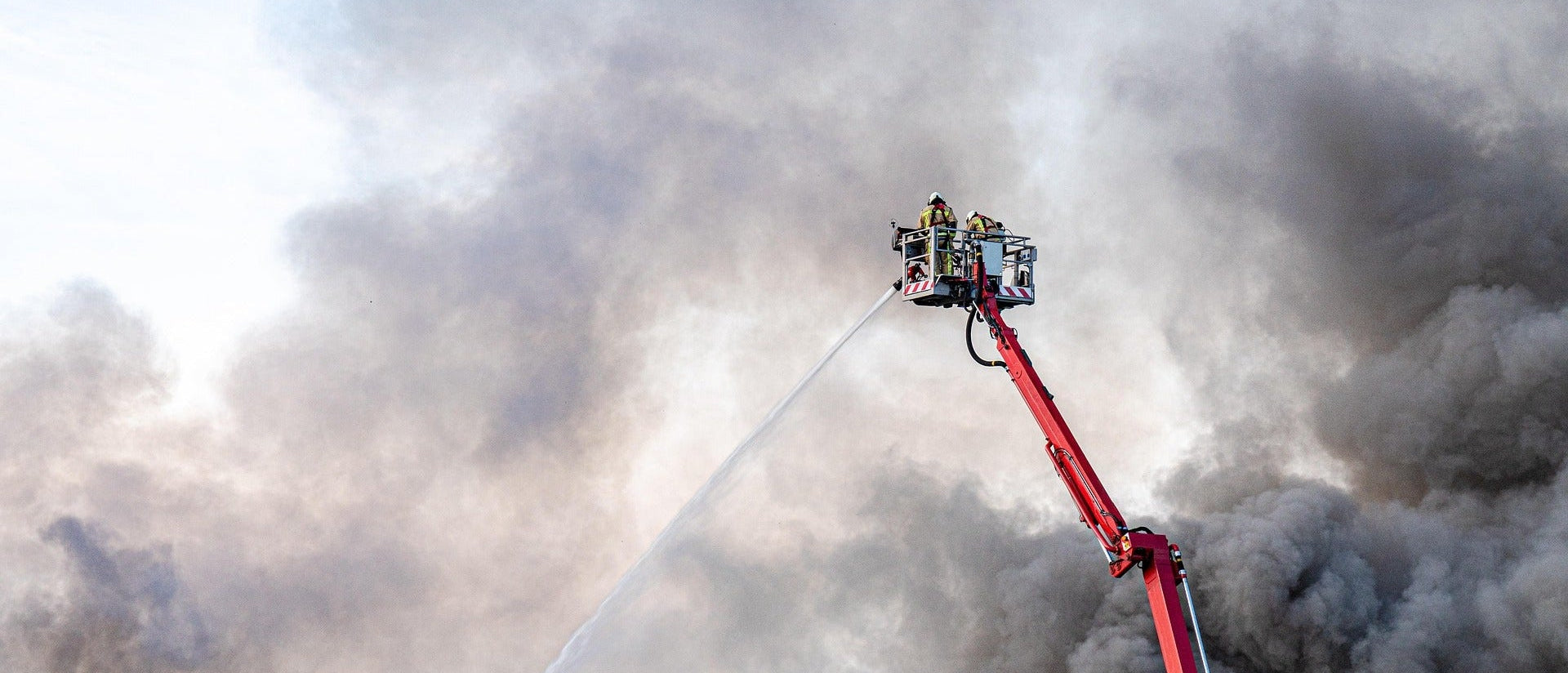 Fire truck's water cannon spraying water amidst thick smoke
